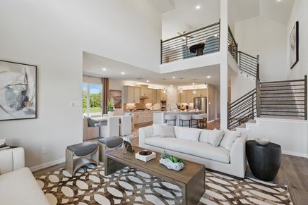 Experience modern elegance with a vaulted ceiling, open-plan kitchen, and chic staircase in Green Oaks Preserve.