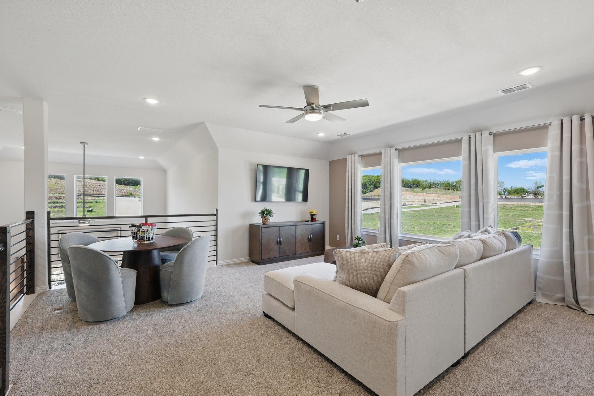 Sophisticated seating area with expansive windows, plush carpeting in Green Oaks Preserve community.