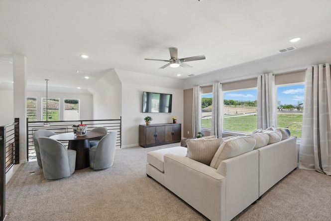 Sophisticated seating area with expansive windows, plush carpeting in Green Oaks Preserve community.