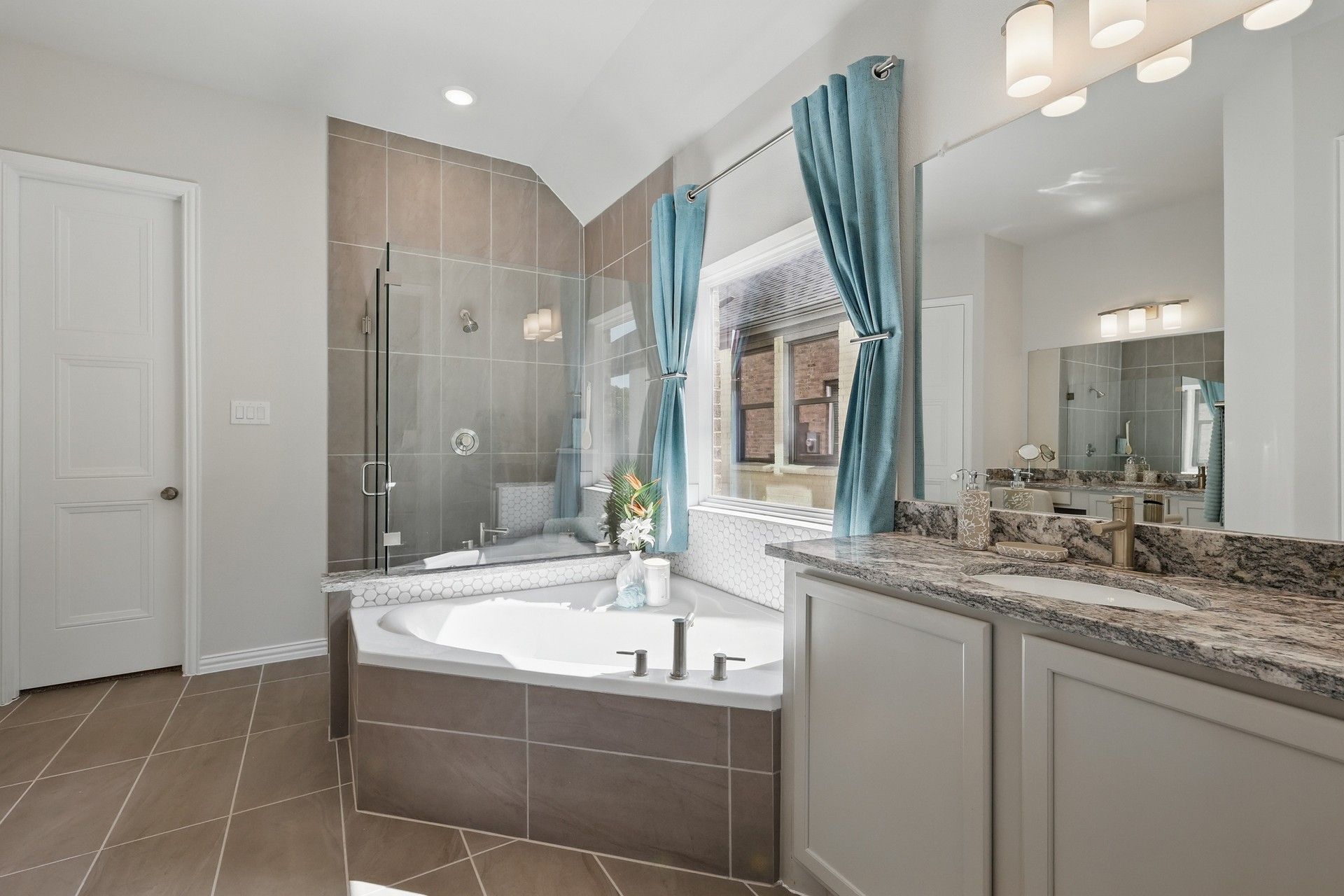 Elegant tub, glass shower, and granite counter enhance this Green Oaks Preserve bathroom's opulence.