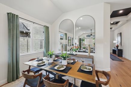 Luxurious dining room with vaulted ceiling and expansive mirrors in Green Oaks Preserve community.