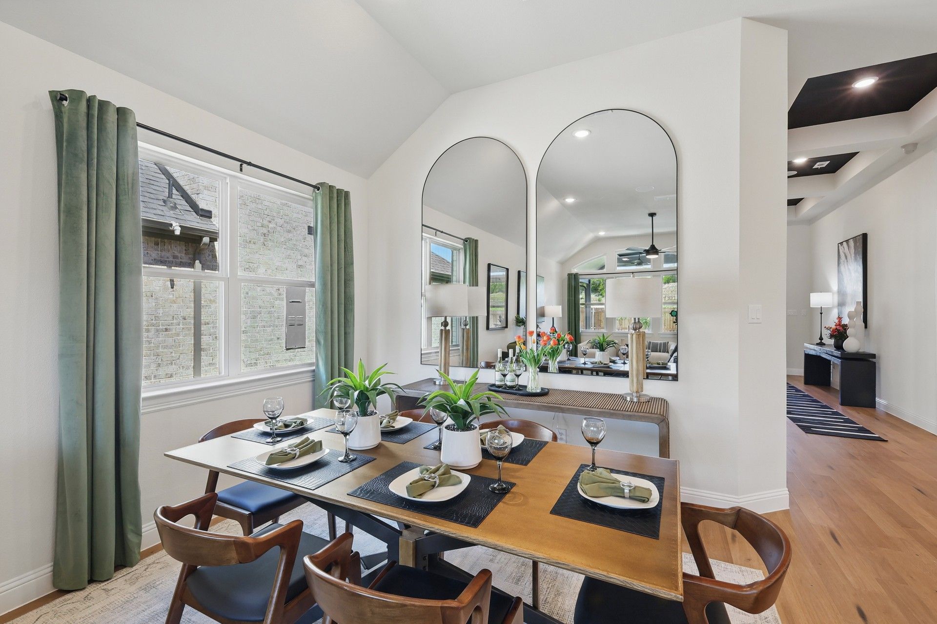 Luxurious dining room with vaulted ceiling and expansive mirrors in Green Oaks Preserve community.