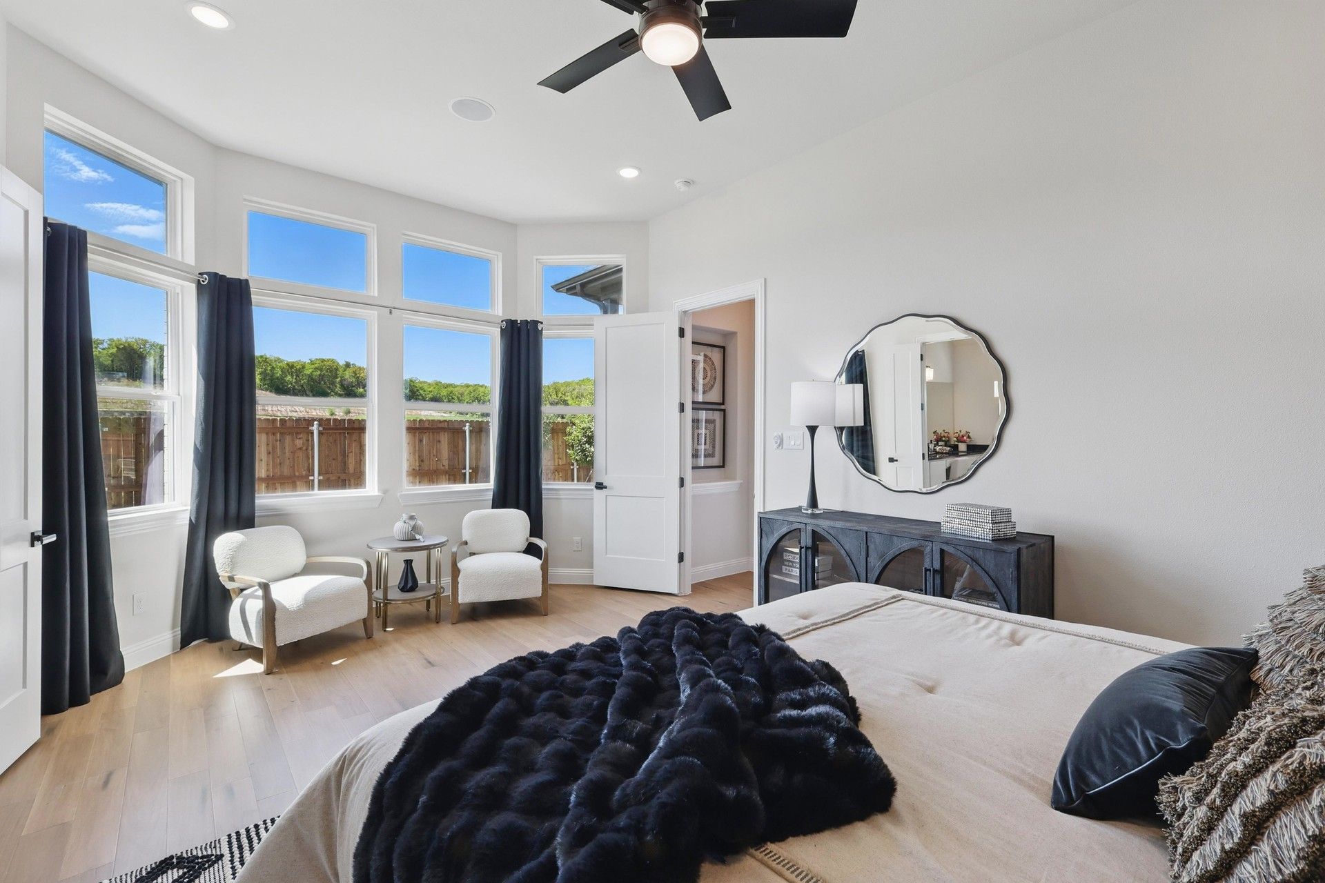 Expansive windows illuminate sleek hardwood floors and elegant decor in Green Oaks Preserve's serene bedroom.