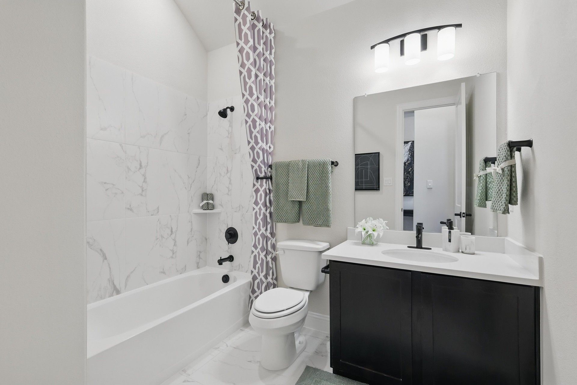 Indulge in elegance with marble tile features and sleek black fixtures in this Green Oaks Preserve bathroom.