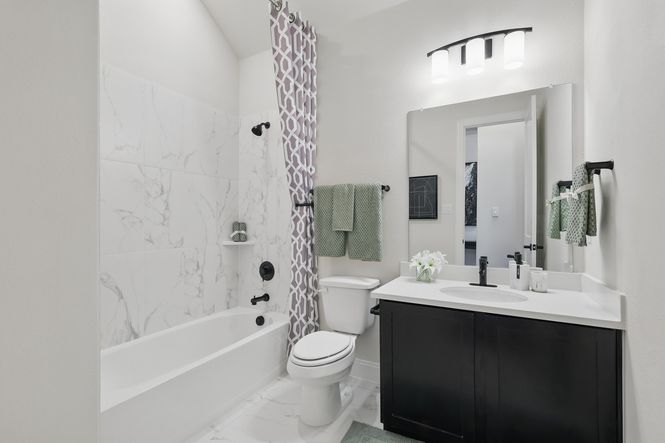 Indulge in elegance with marble tile features and sleek black fixtures in this Green Oaks Preserve bathroom.