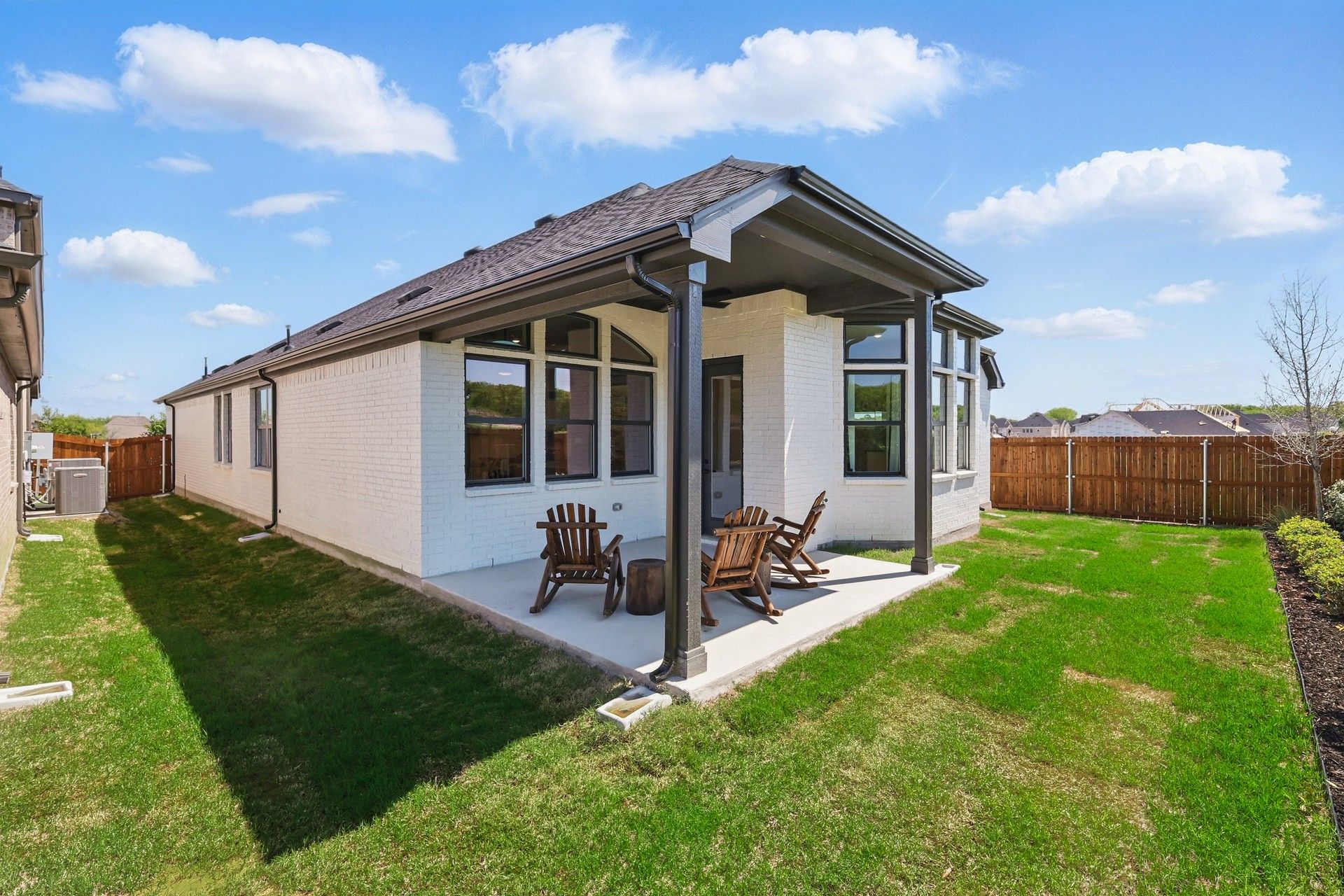 Luxurious white brick facade with spacious patio, elegant gable roof; Green Oaks Preserve.