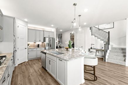 Exquisite marble island and sleek pendant lighting enhance this Green Oaks Preserve kitchen.