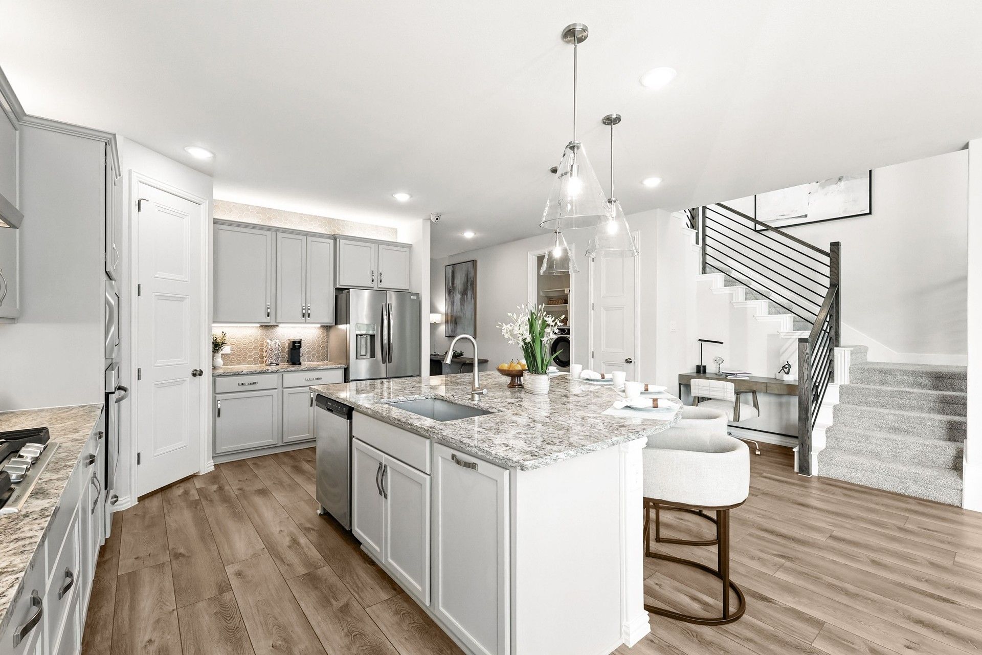 Exquisite marble island and sleek pendant lighting enhance this Green Oaks Preserve kitchen.