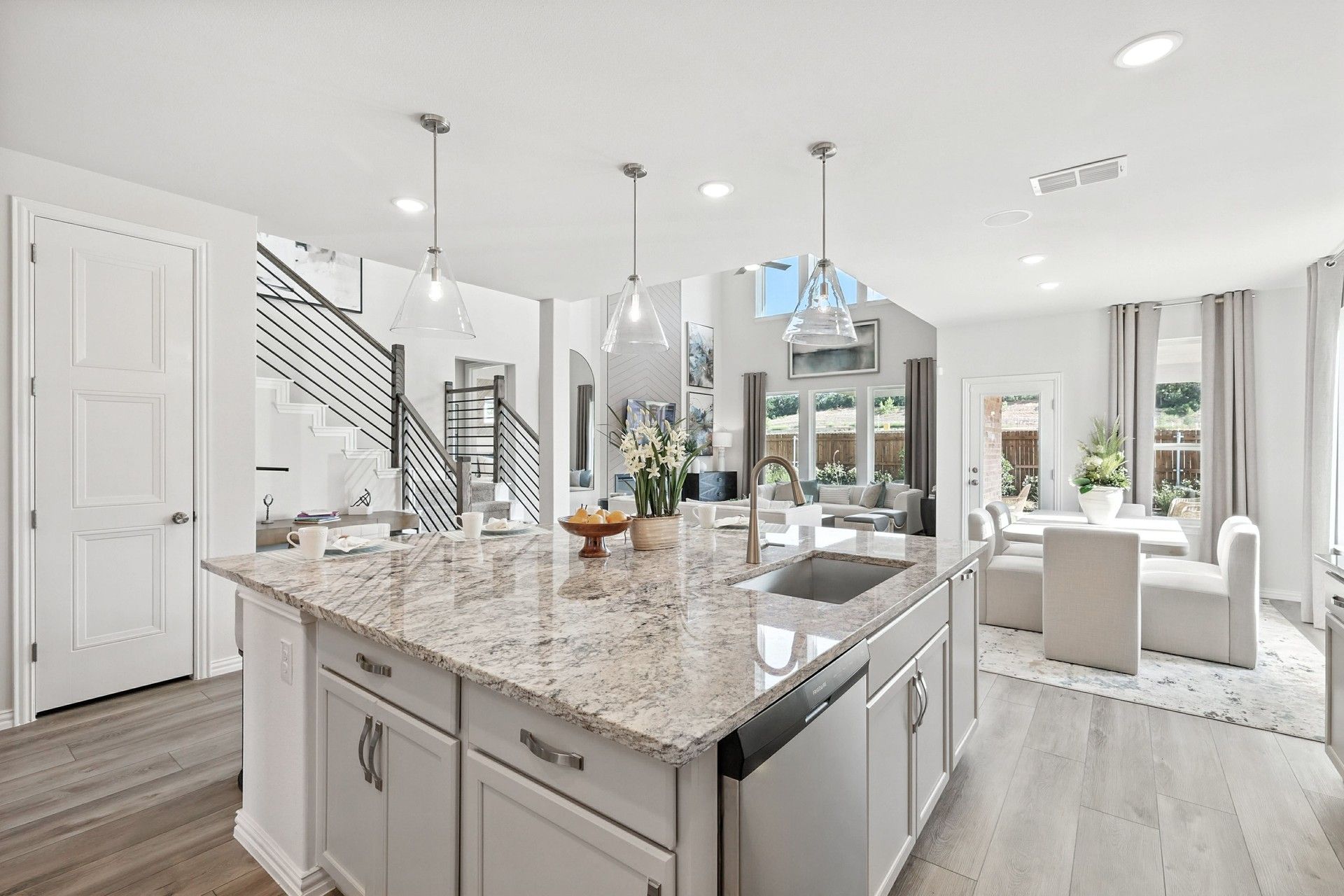 Granite countertops, sleek lighting, and airy space define this Green Oaks Preserve home's sophisticated kitchen.