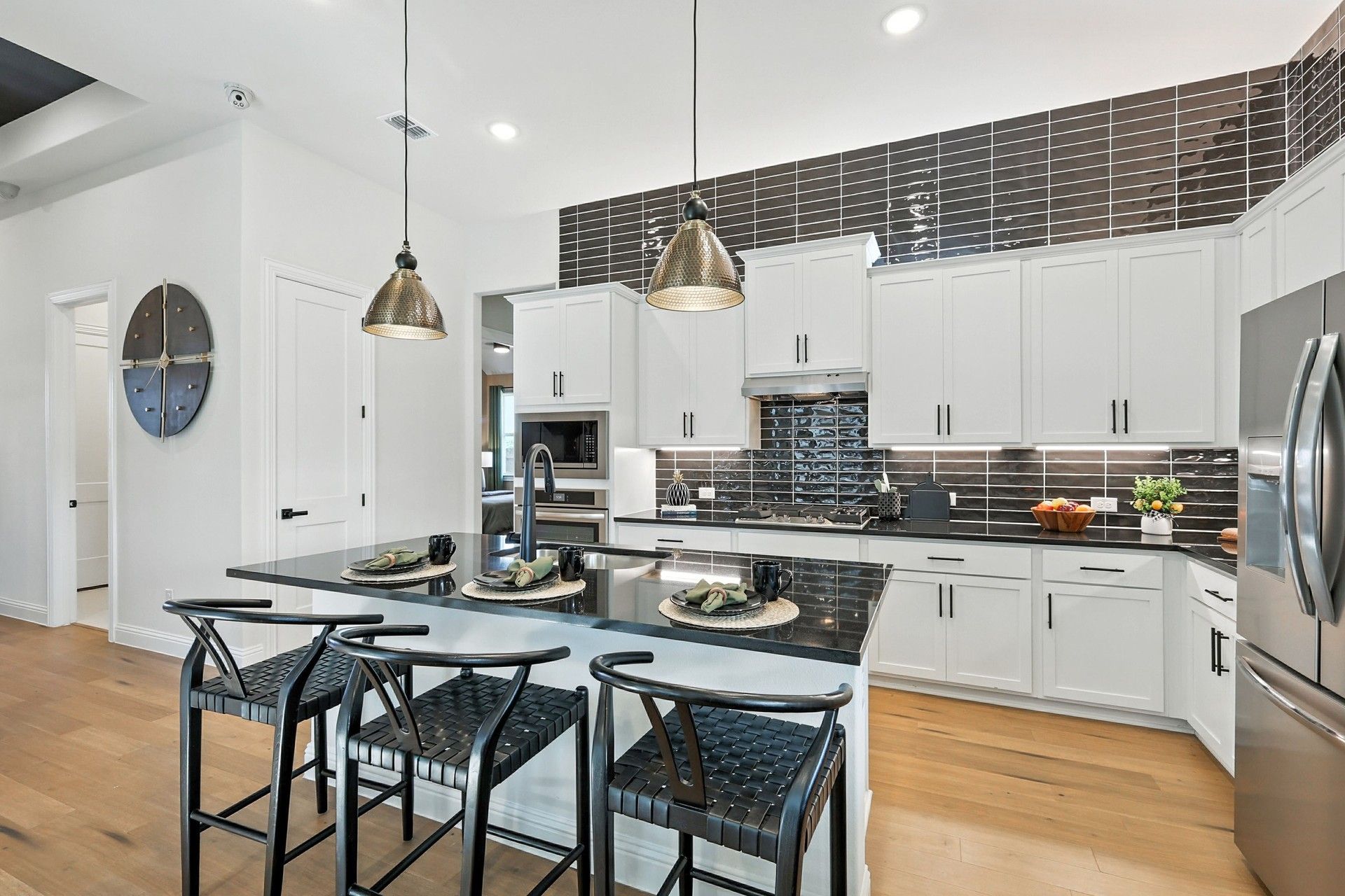 Sleek white cabinetry and glossy black tiles define this exquisite kitchen in Green Oaks Preserve.