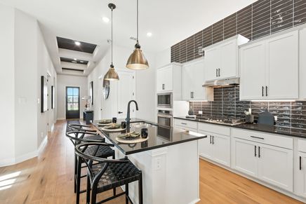Elegant white cabinetry and black granite countertops exemplify sophistication in Green Oaks Preserve.