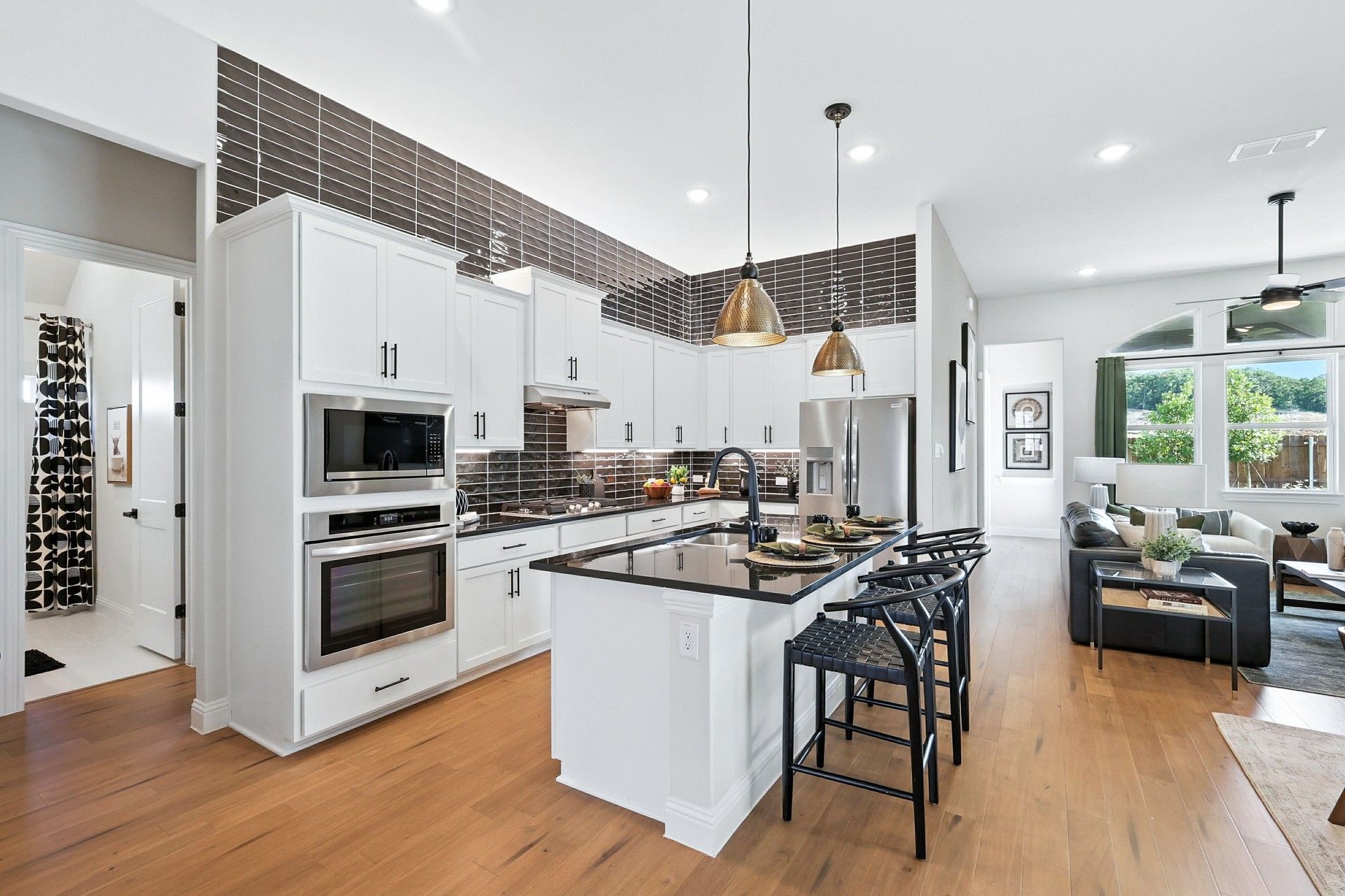 Elegant kitchen features chic black countertops, pendant lighting, and exquisite wood flooring in Green Oaks Preserve.