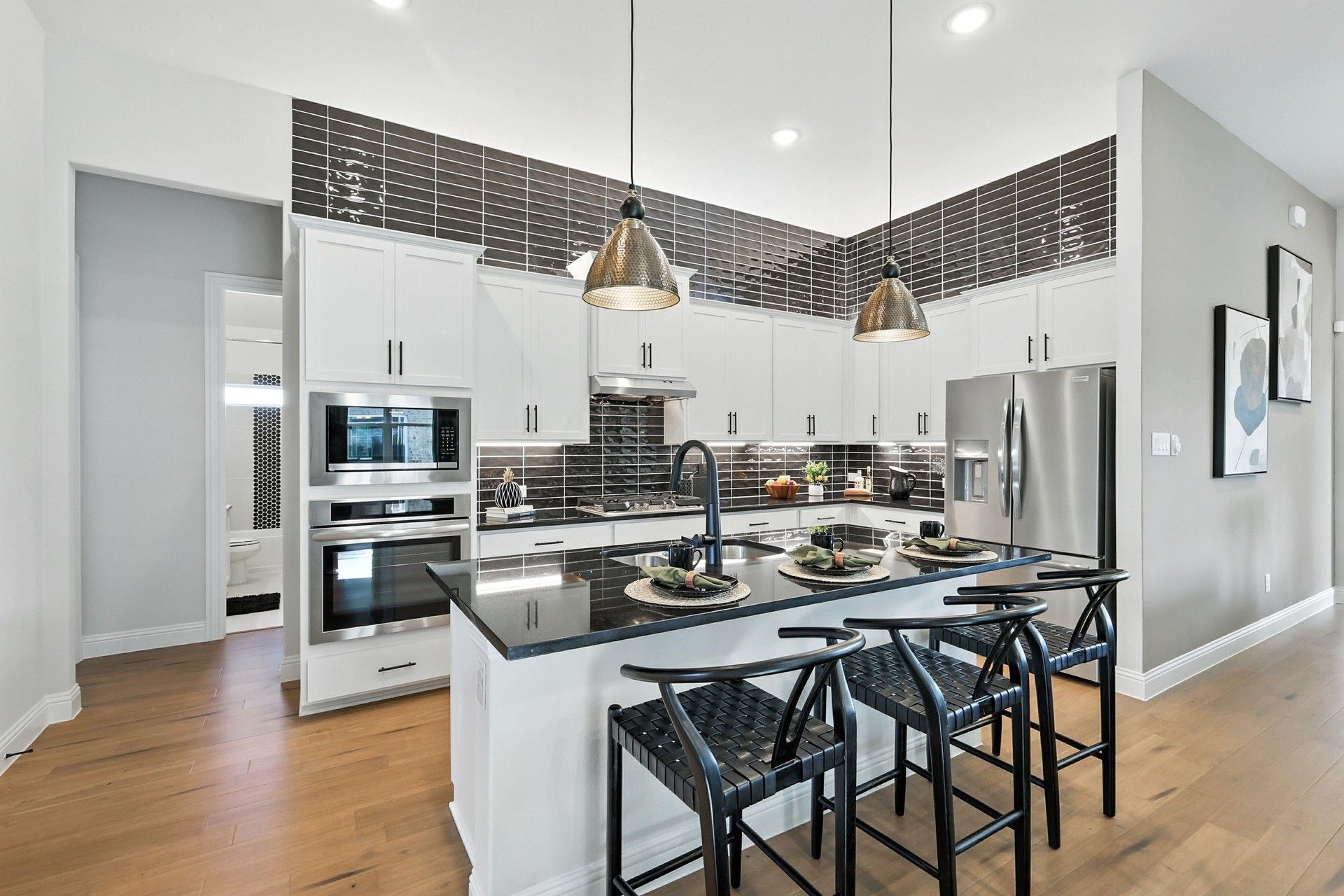 Elegant kitchen features sleek black countertops and pendant lighting. Located in prestigious Green Oaks Preserve.