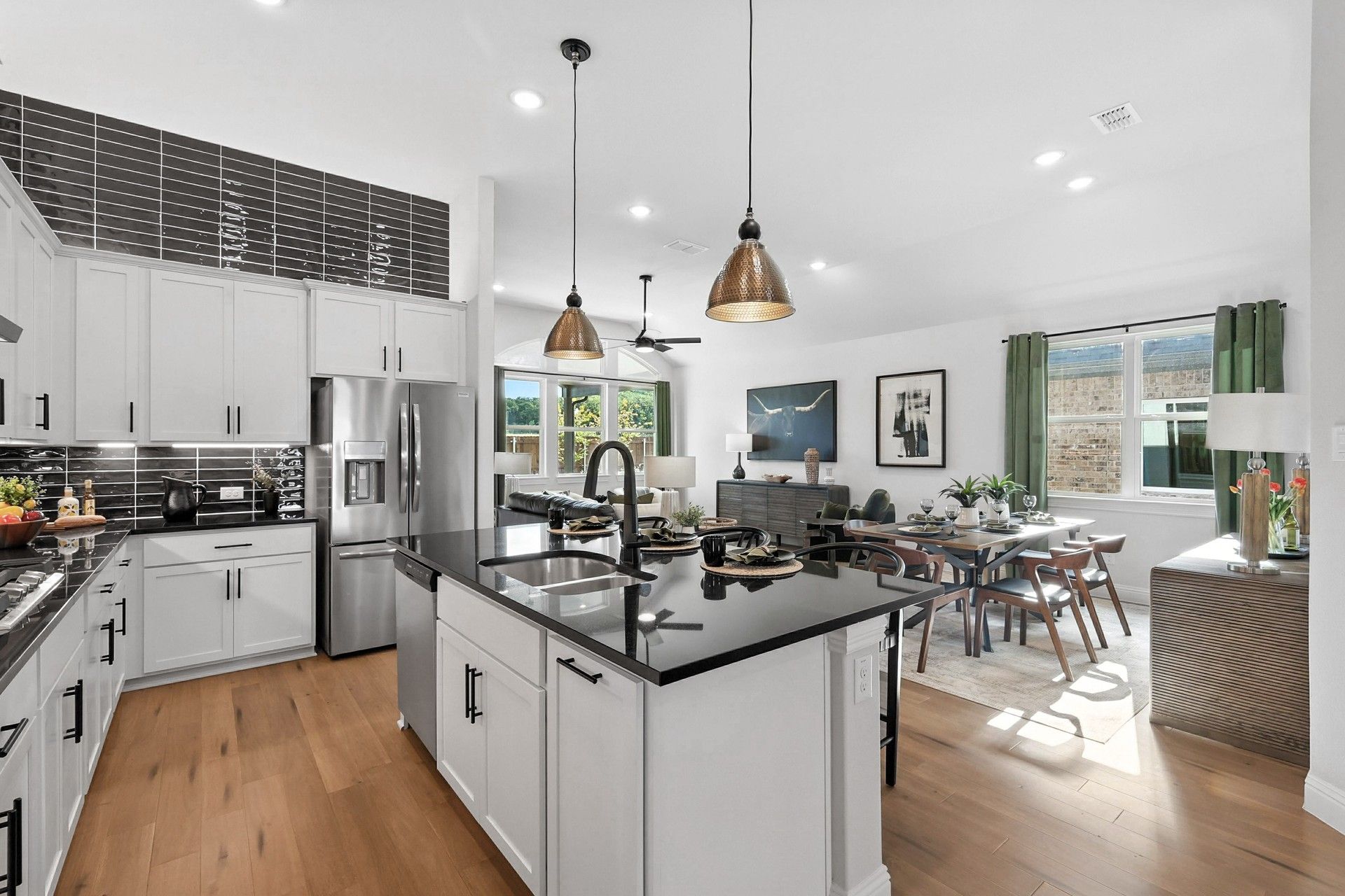 Explore elegance at Green Oaks Preserve. White cabinetry, sleek black countertops, exquisite lighting in a spacious layout.