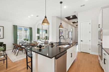Sleek black countertops and luxurious hardwood floors make this kitchen a standout in Green Oaks Preserve.