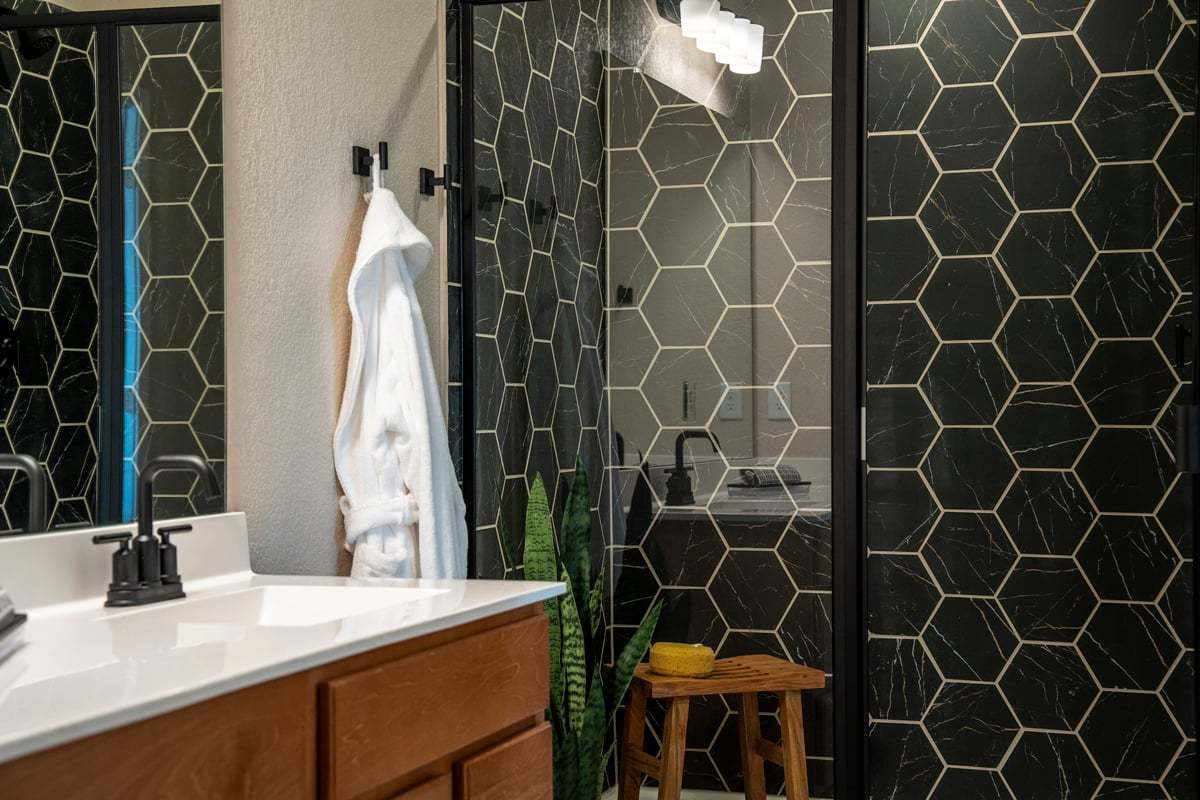 Plan 1676 Modeled -  Walk-in shower with hexagon tile surround and matte black enclosure at primary bath