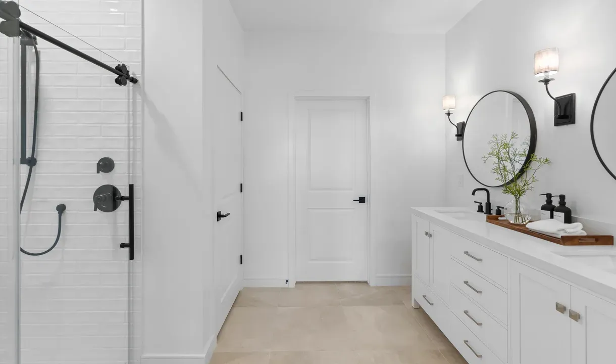 Primary bath with circular mirrors and matte black fixtures