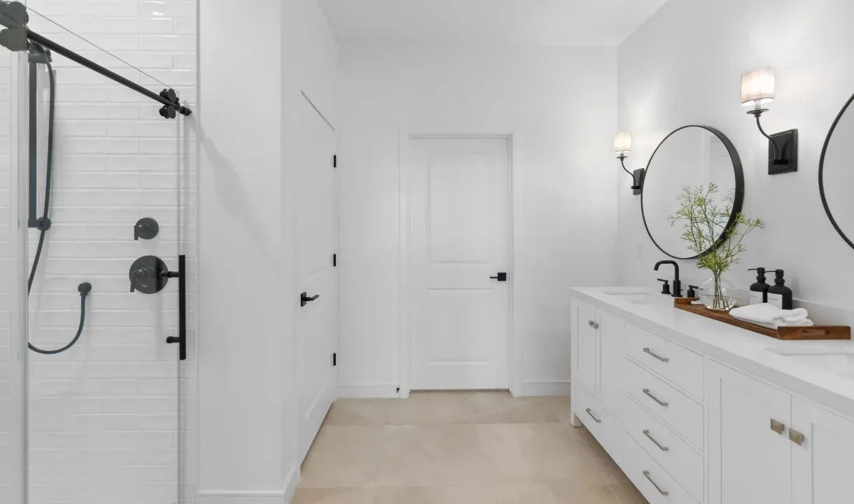 Primary bath with circular mirrors and matte black fixtures