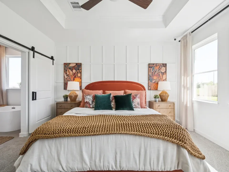 Primary suite with decorative feature wall and sliding barn door to private bath