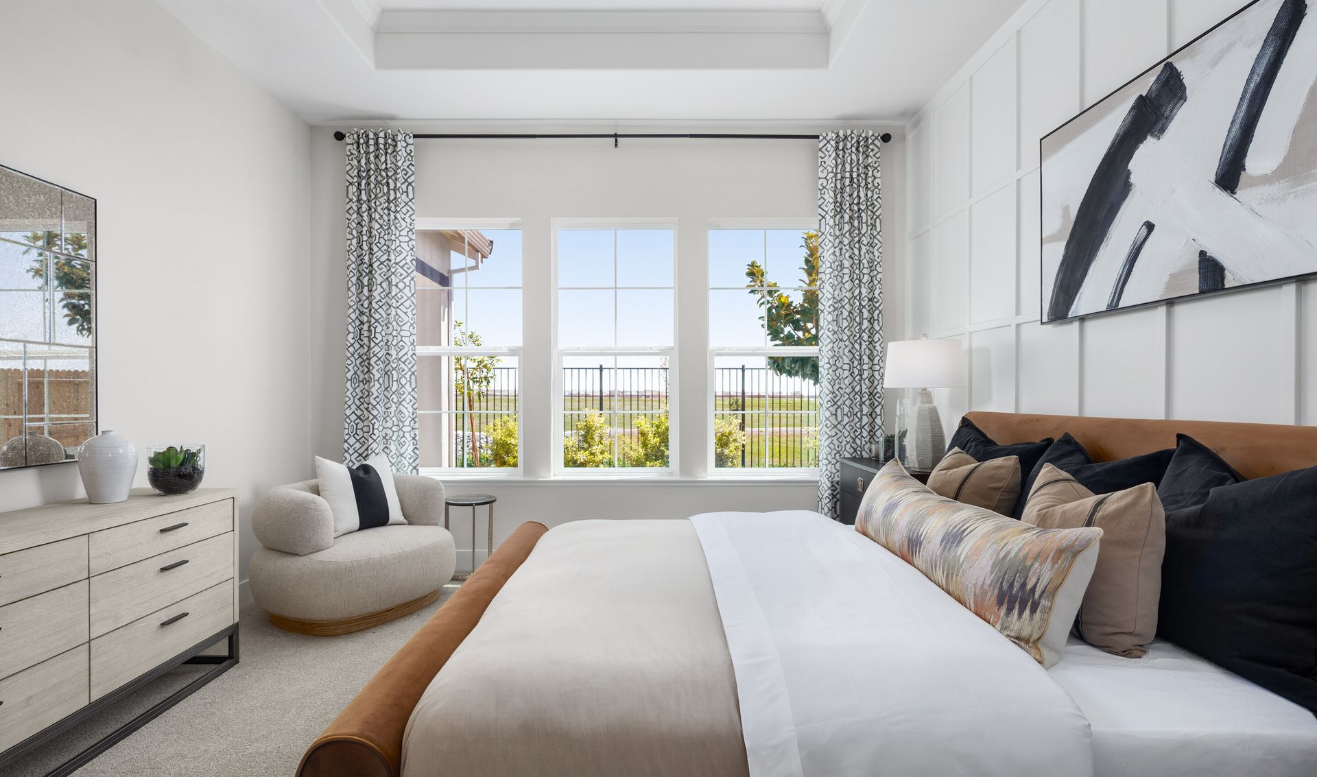 Primary suite with decorative feature wall and tray ceiling