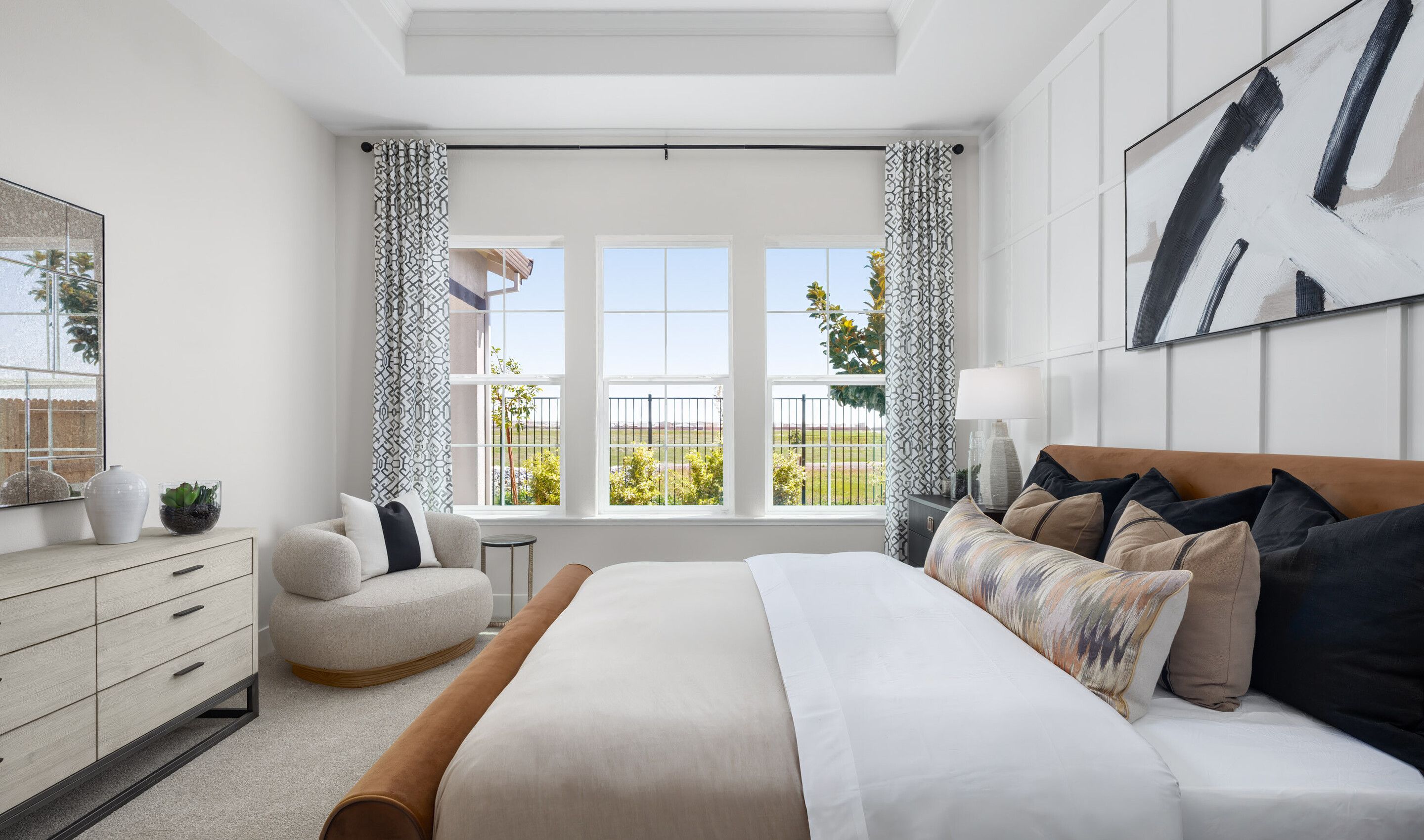 Primary suite with decorative feature wall and tray ceiling
