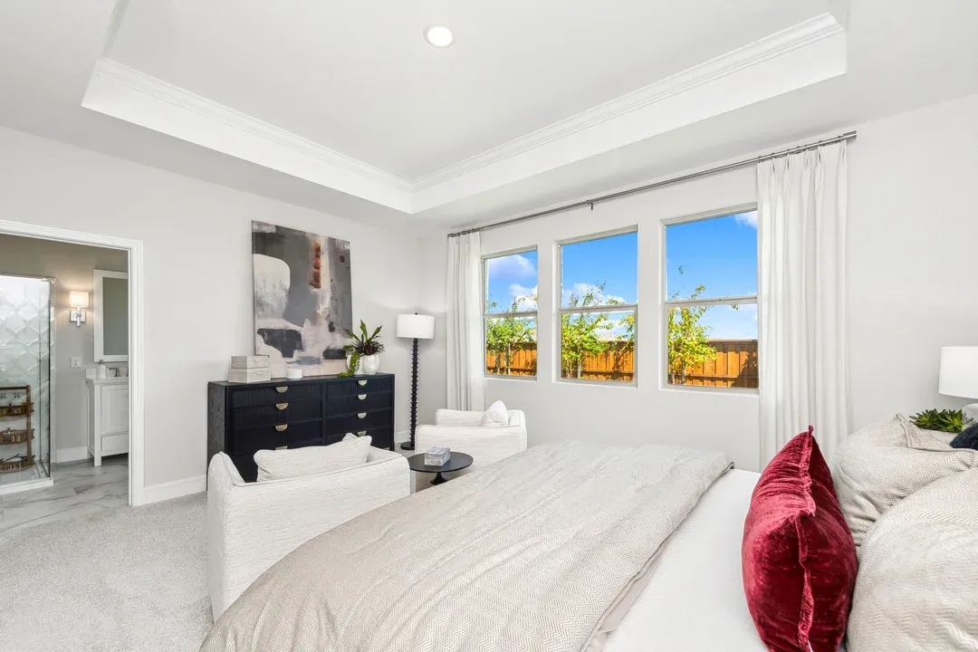 Primary suite with crown moulding in coffered ceiling and plush carpeting