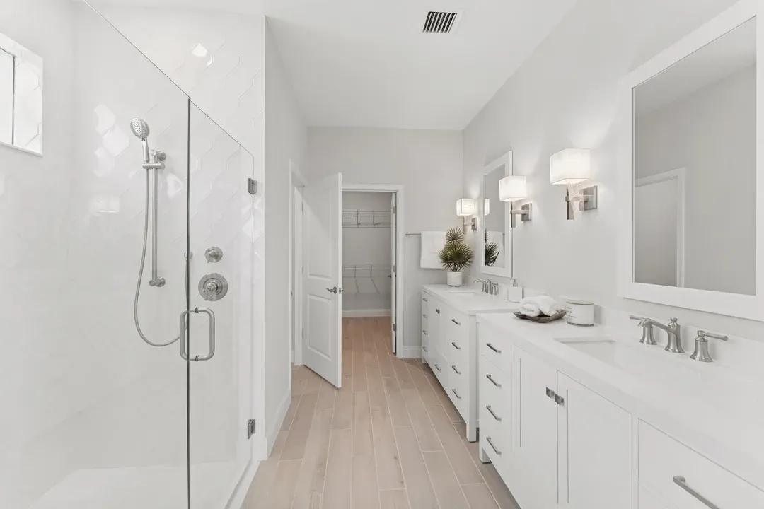 Primary bath with freestanding vanities and glass shower enclosure