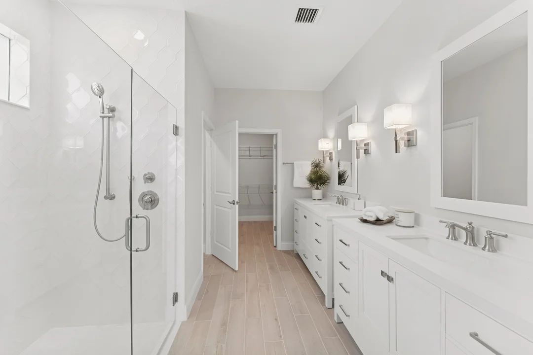 Primary bath with freestanding vanities and glass shower enclosure