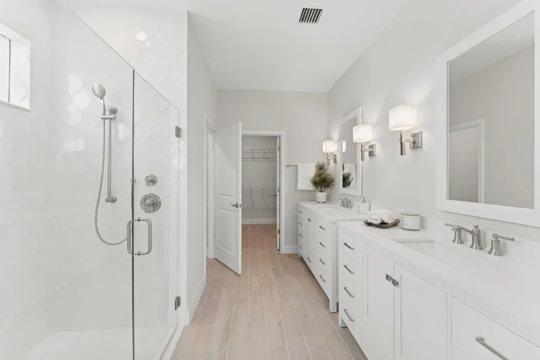 Primary bath with freestanding vanities and glass shower enclosure