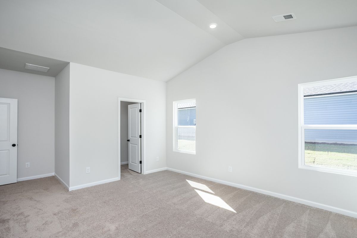 The master bedroom has large windows and carpet.
