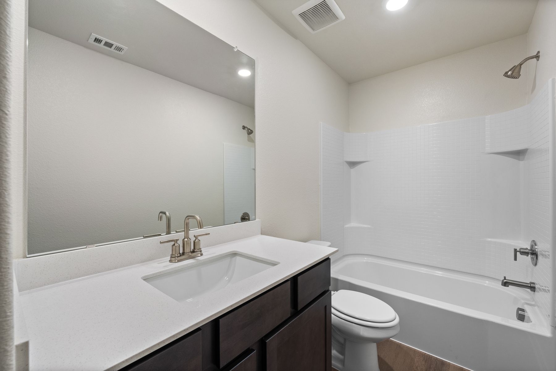 The secondary bathroom has a large vanity space and shower-tub combo.
