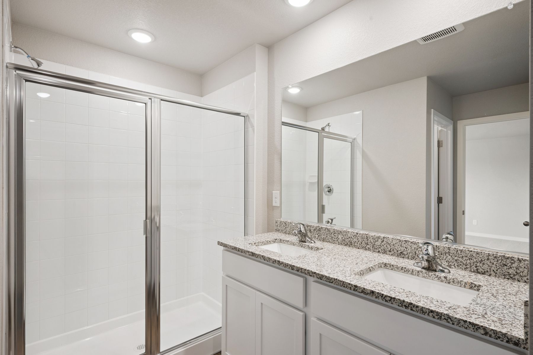 The master bathroom has a dual sink vanity and step in shower. 