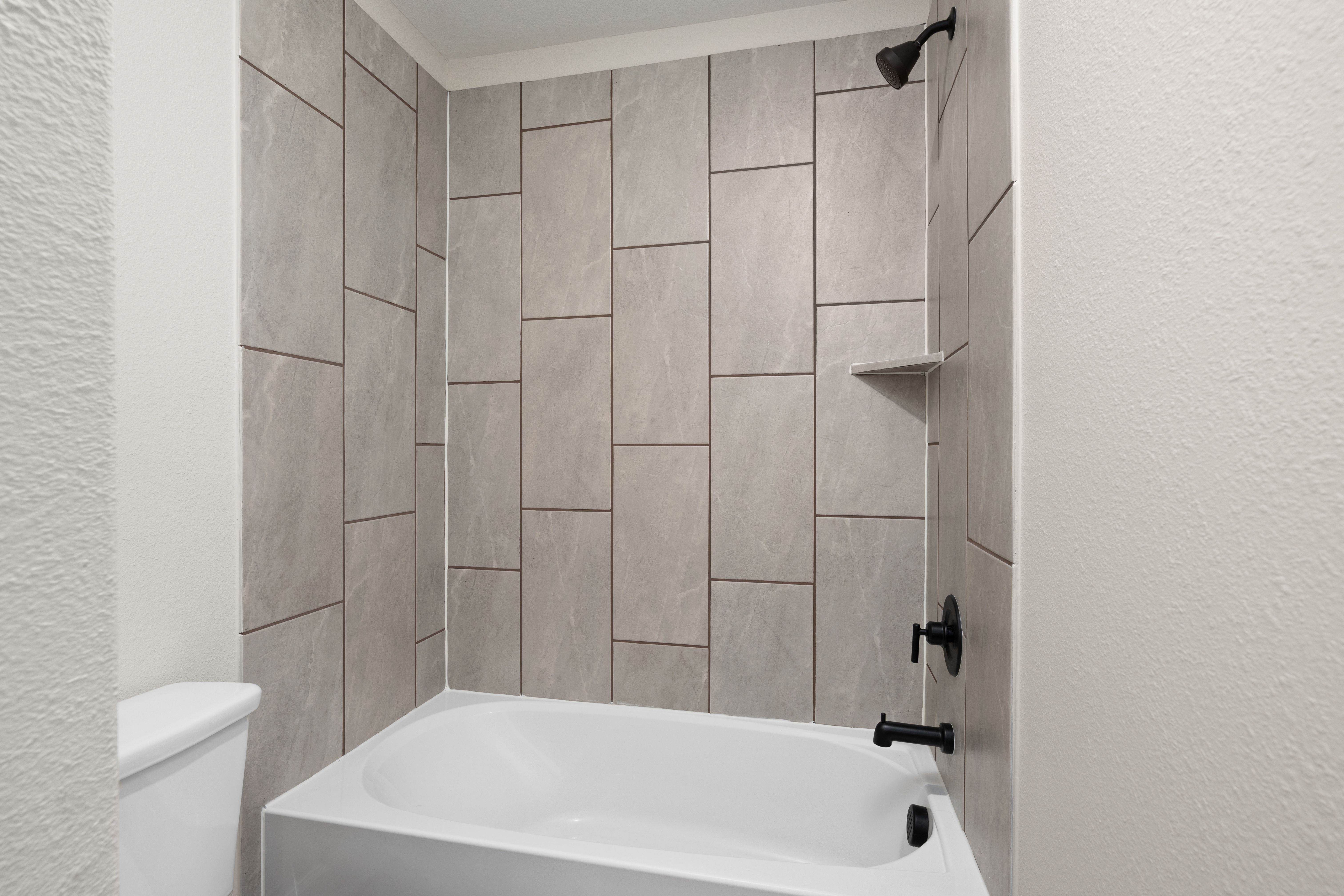 The secondary bathroom has a tiled shower-tub combo.