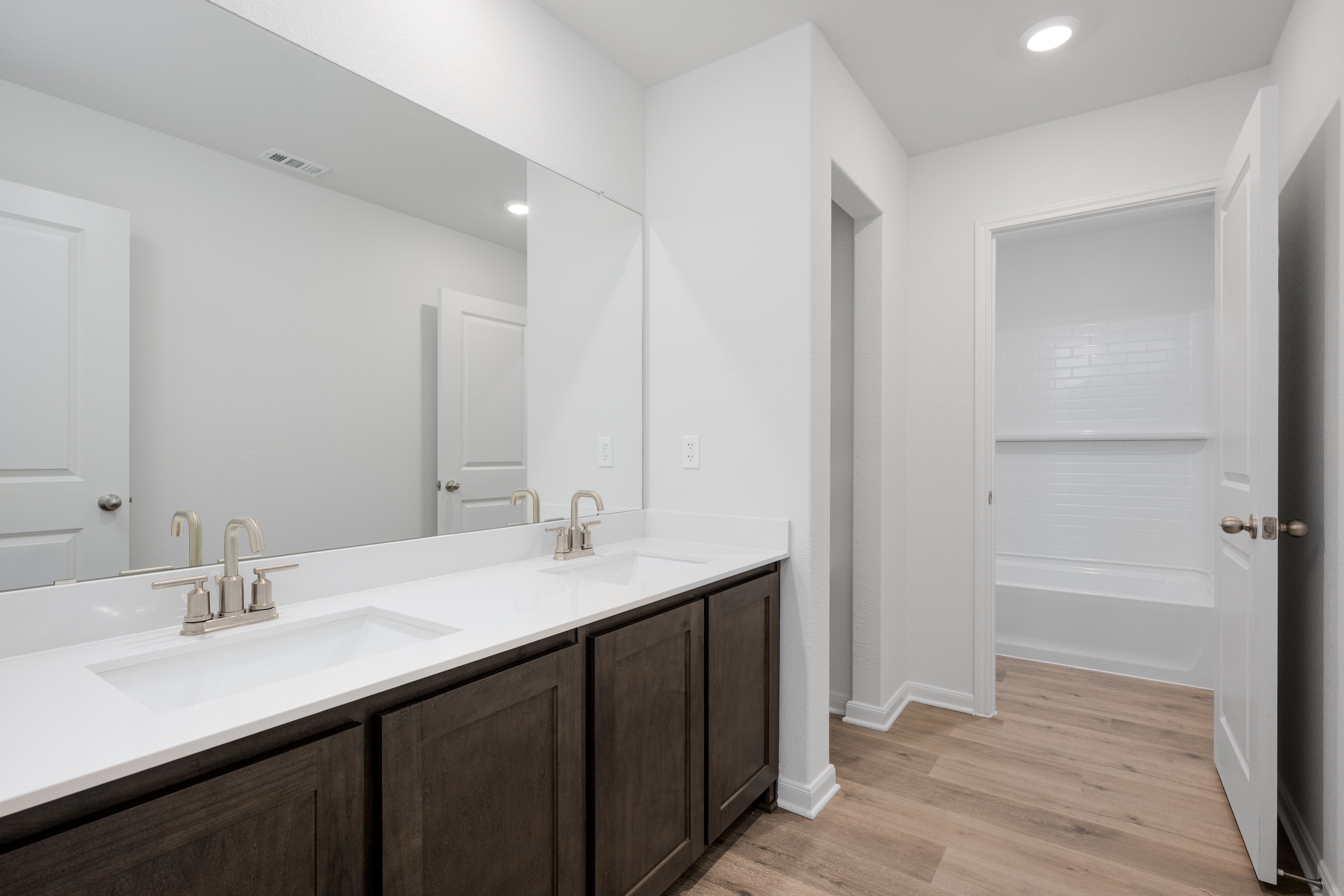 The secondary bathroom has a large vanity space and a shower-tub combo.