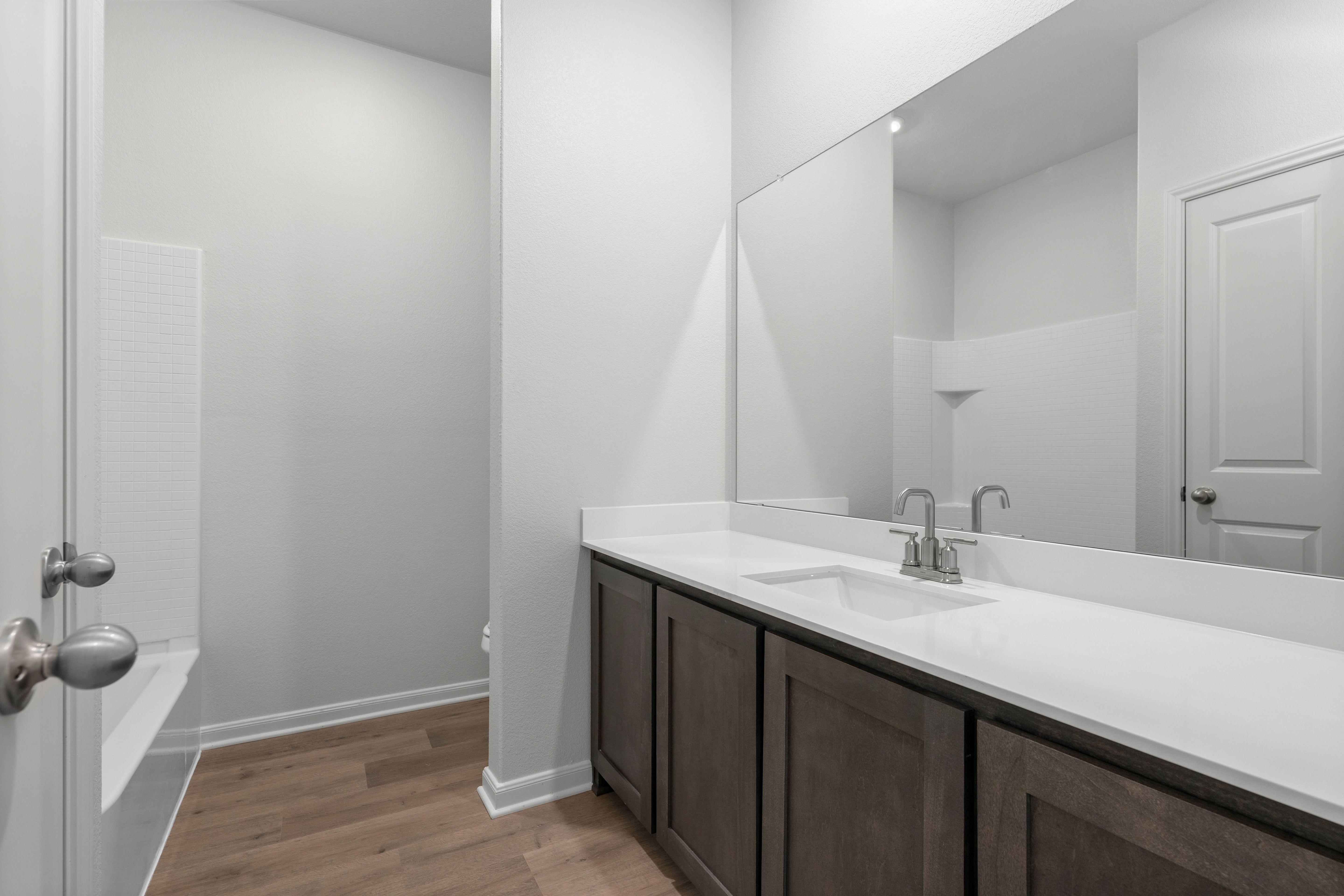 The secondary bathroom has a large vanity space and a shower-tub combo.
