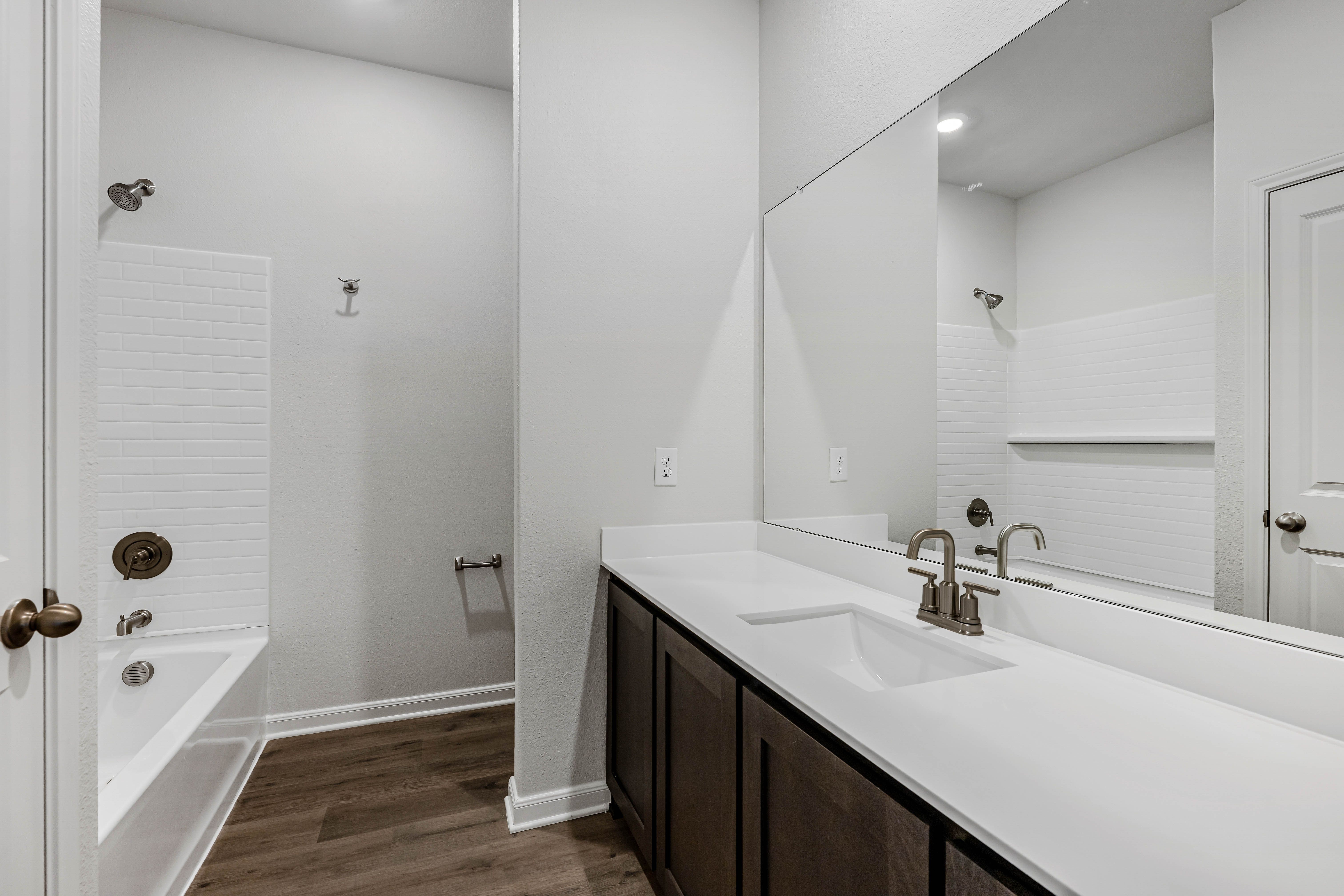 The secondary bathroom has a sprawling vanity and a shower-tub combo.
