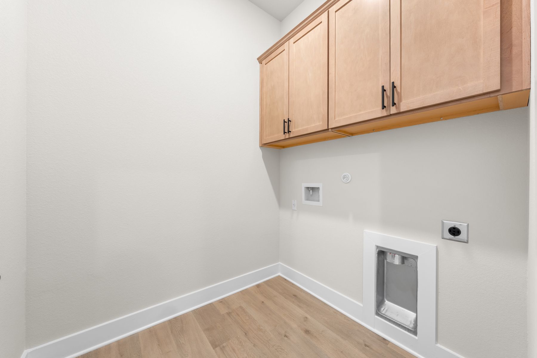 The laundry room has upper cabinetry for storage.