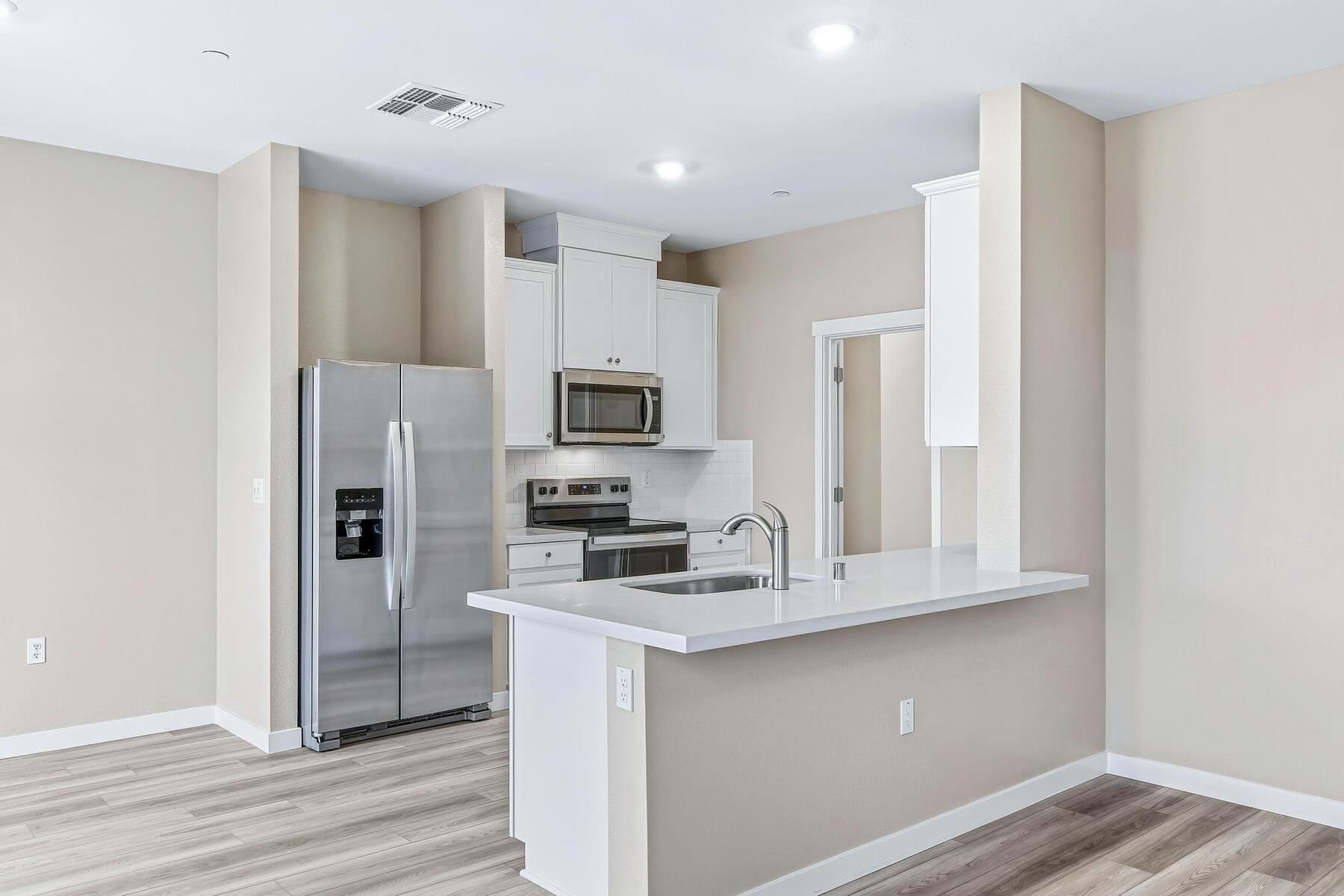 The kitchen has stainless steel appliances and plank flooring