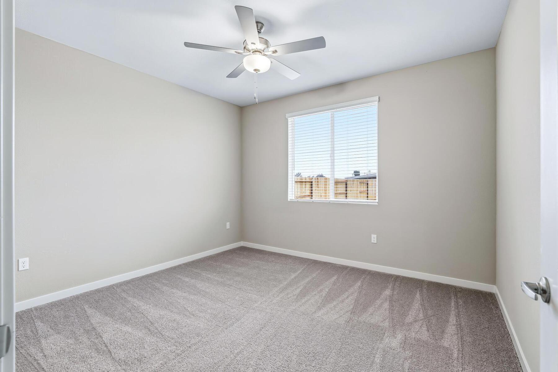The master bedroom is spacious with a ceiling fan.