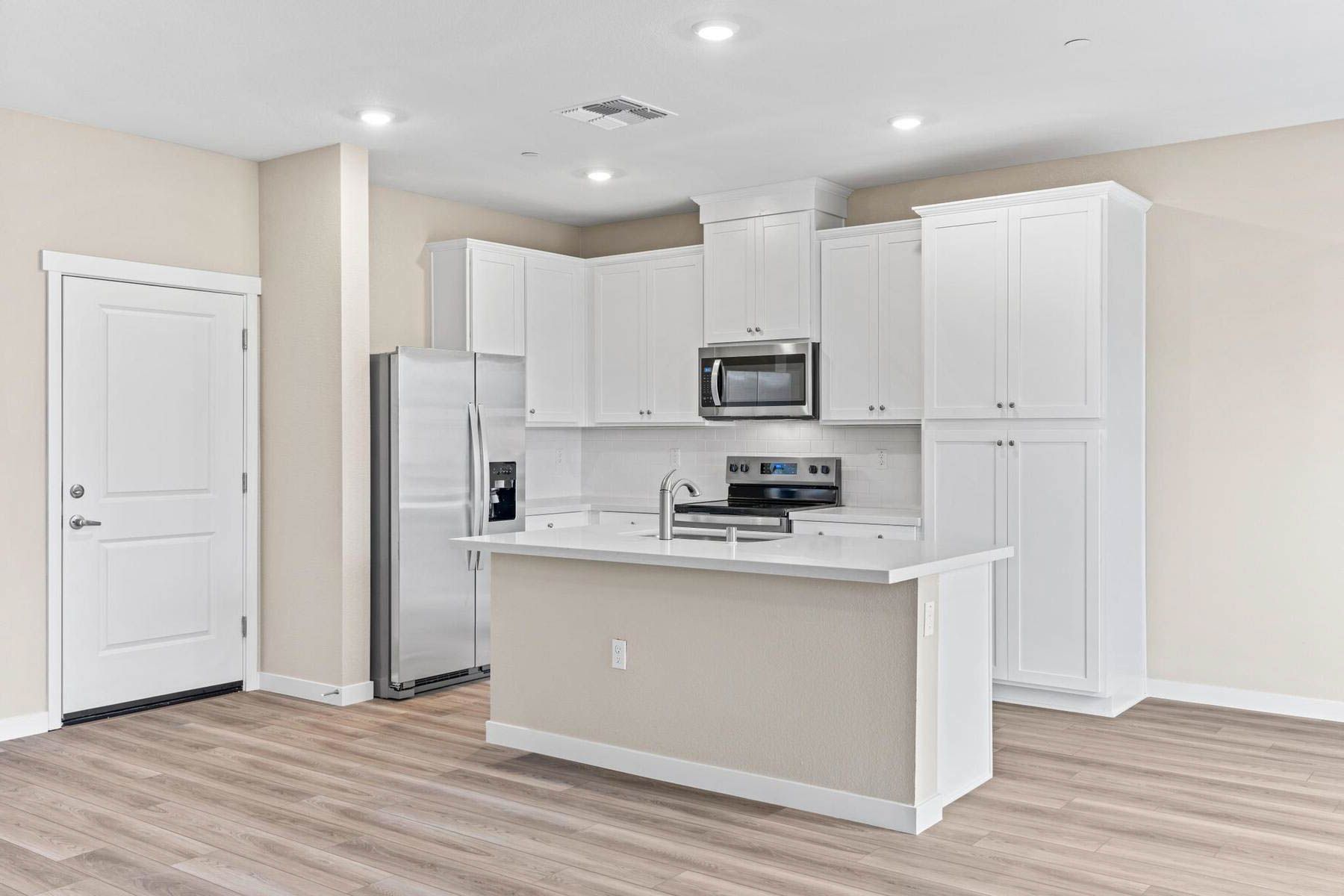 The kitchen has stainless steel appliances and plank flooring.