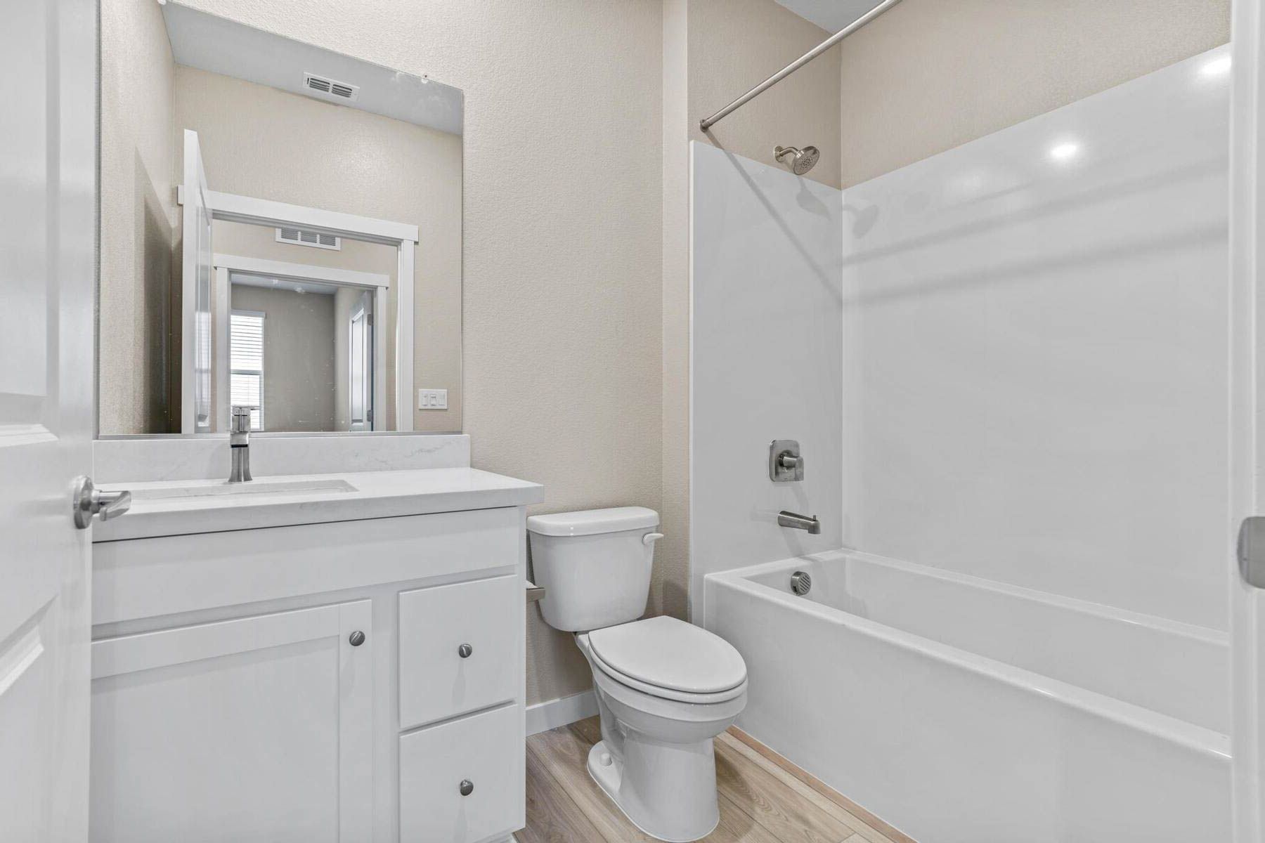 The secondary bathroom has a large vanity and shower/tub combo.