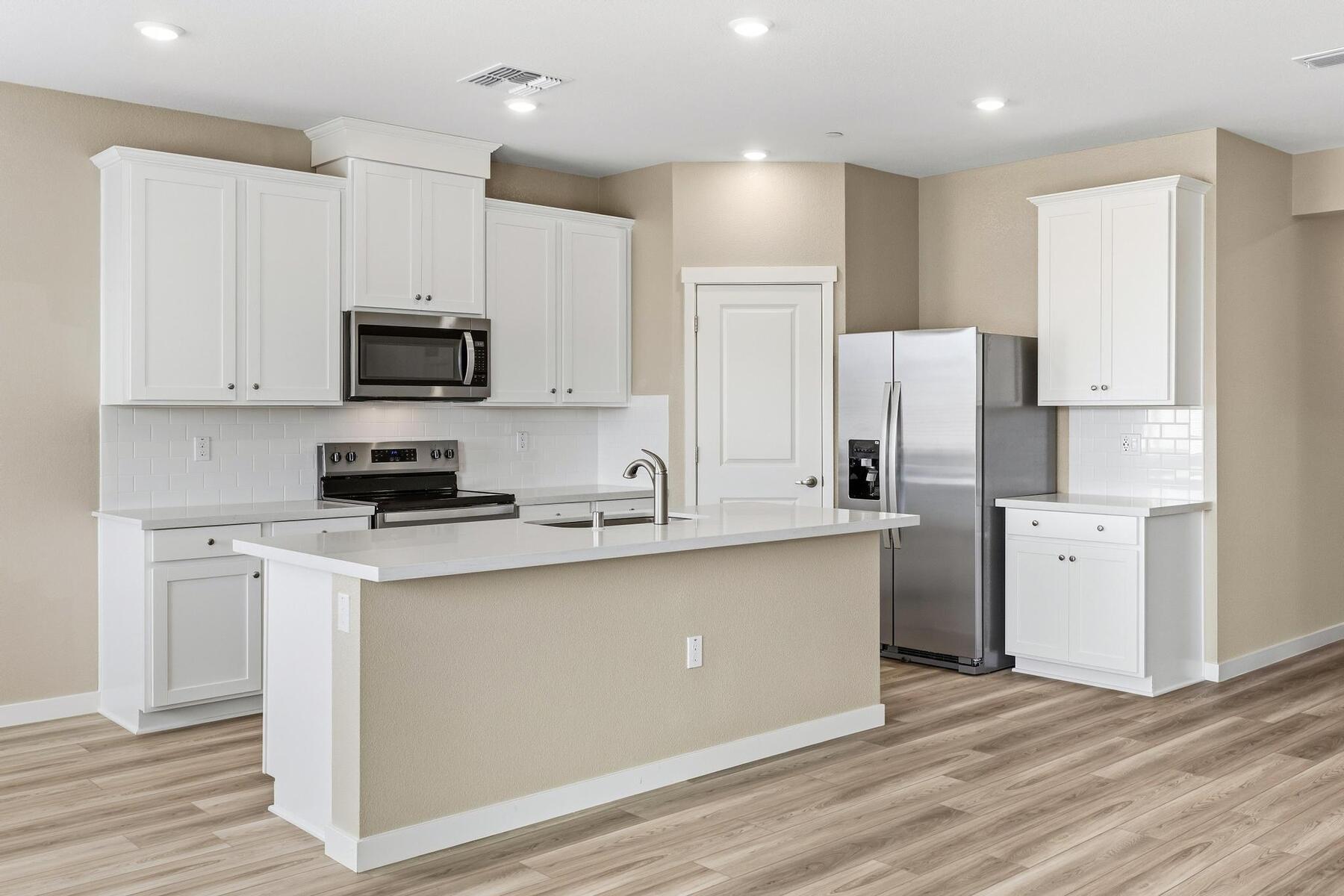 The kitchen has stainless steel appliances and plank flooring.