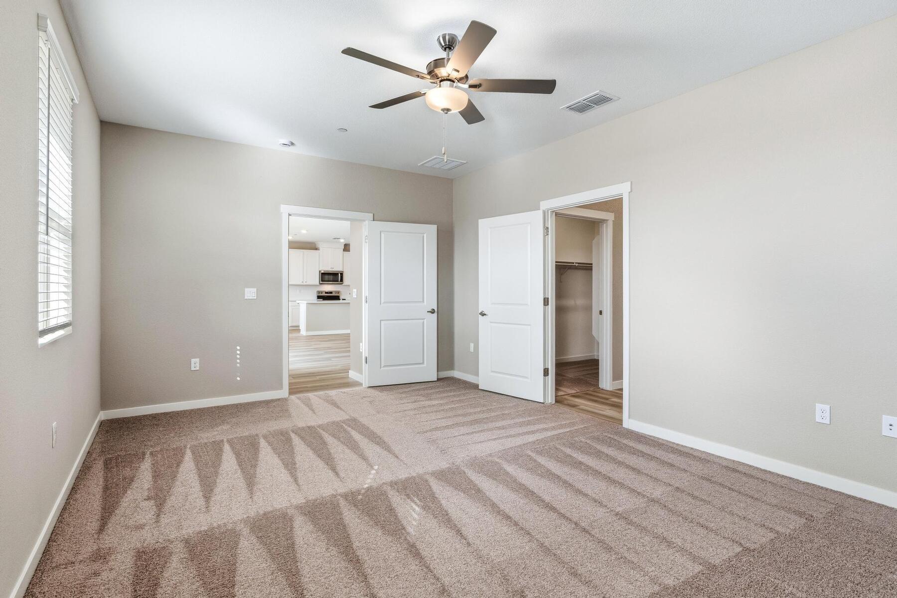 The master bedroom is spacious with a ceiling fan.