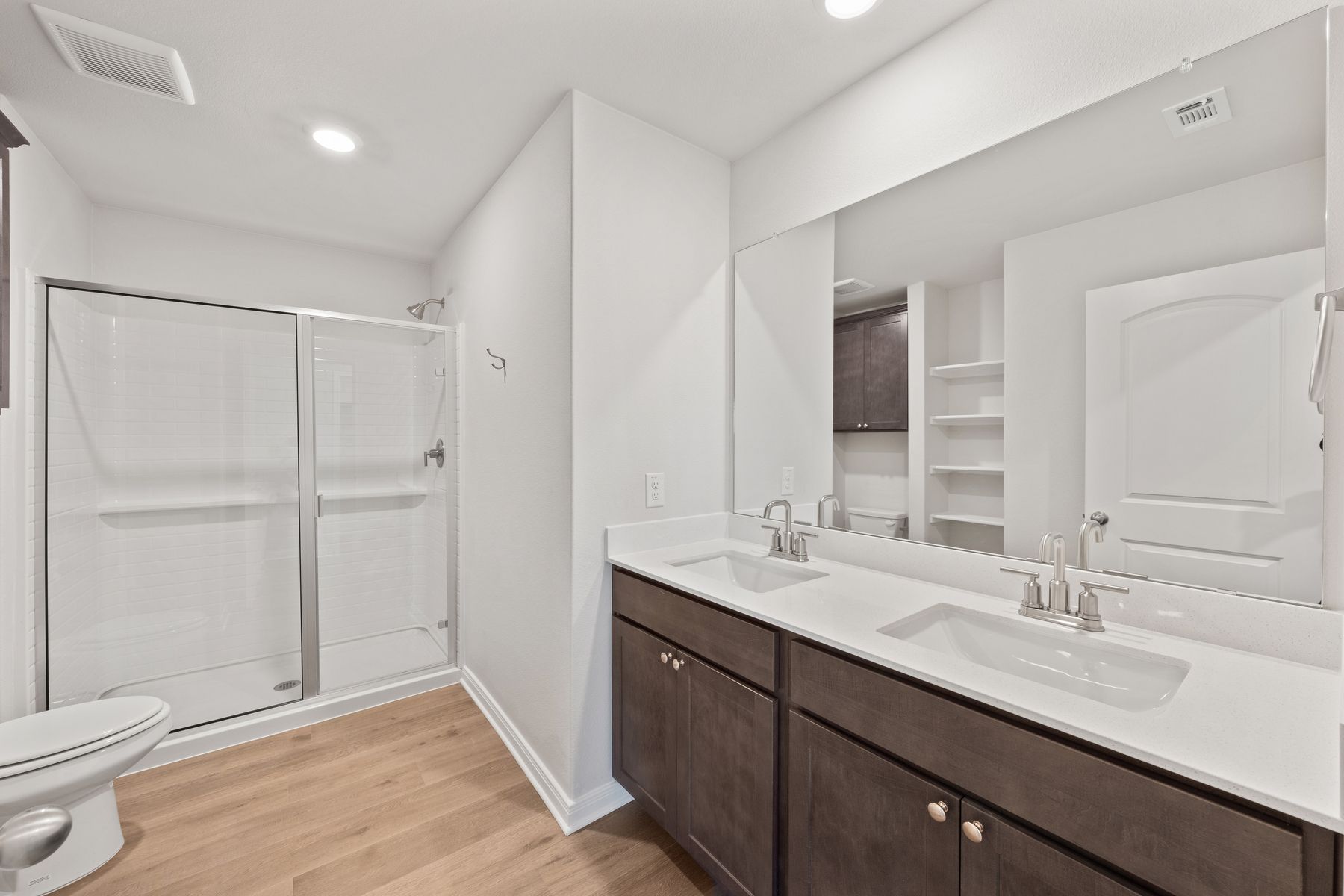 The master bathroom has a sprawling dual-sink vanity and glass, walk-in shower.