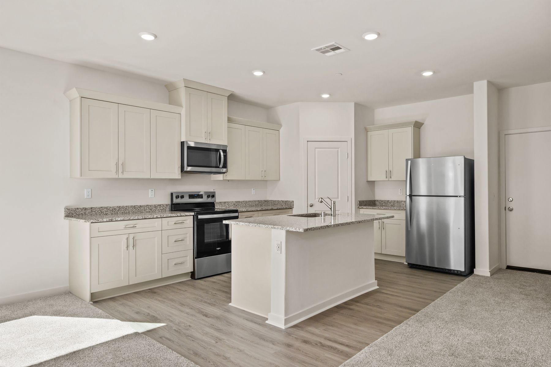The kitchen has stainless steel appliances and plank flooring.