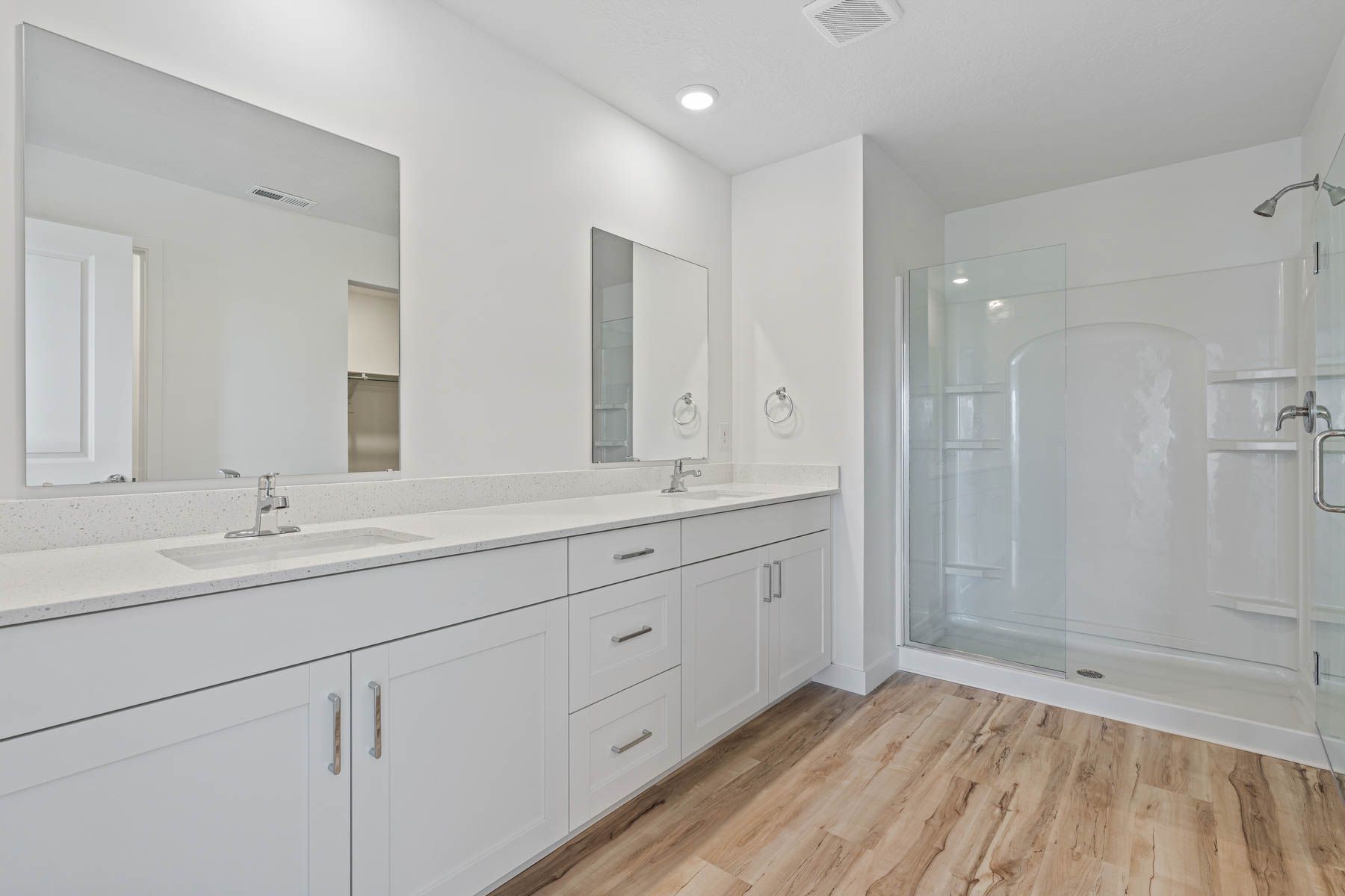The master bathroom has a sprawling dual-sink vanity and glass, walk-in shower.