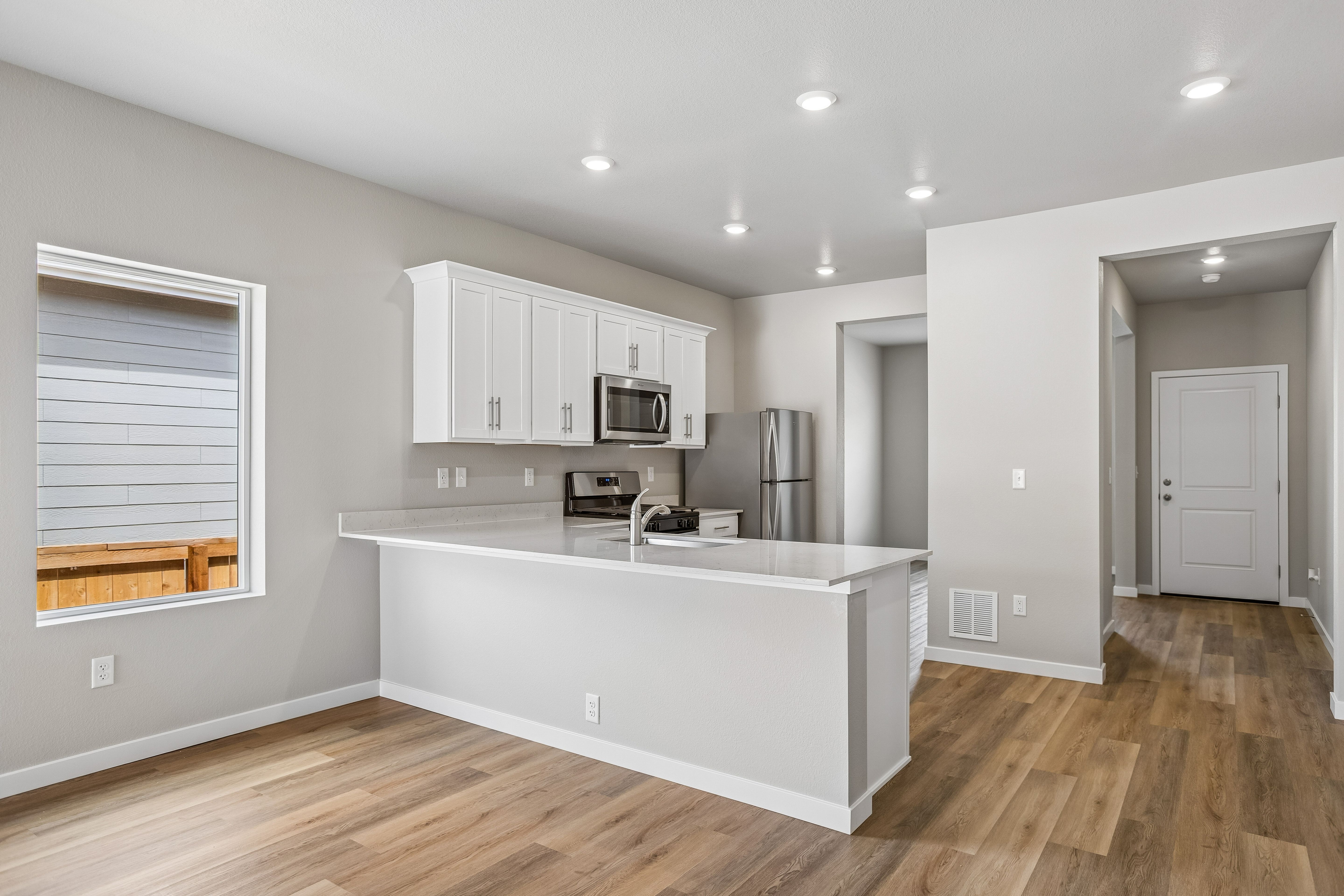 The kitchen has stainless steel appliances and plank flooring.