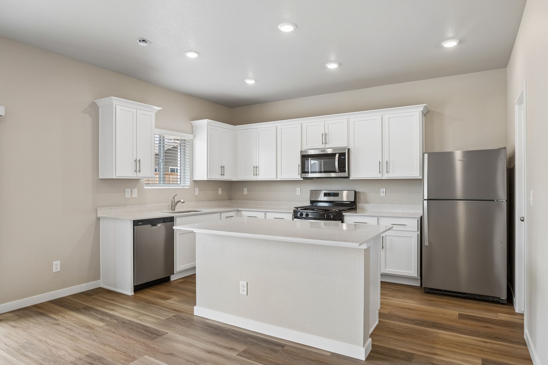 The kitchen has stainless steel appliances and plank flooring.