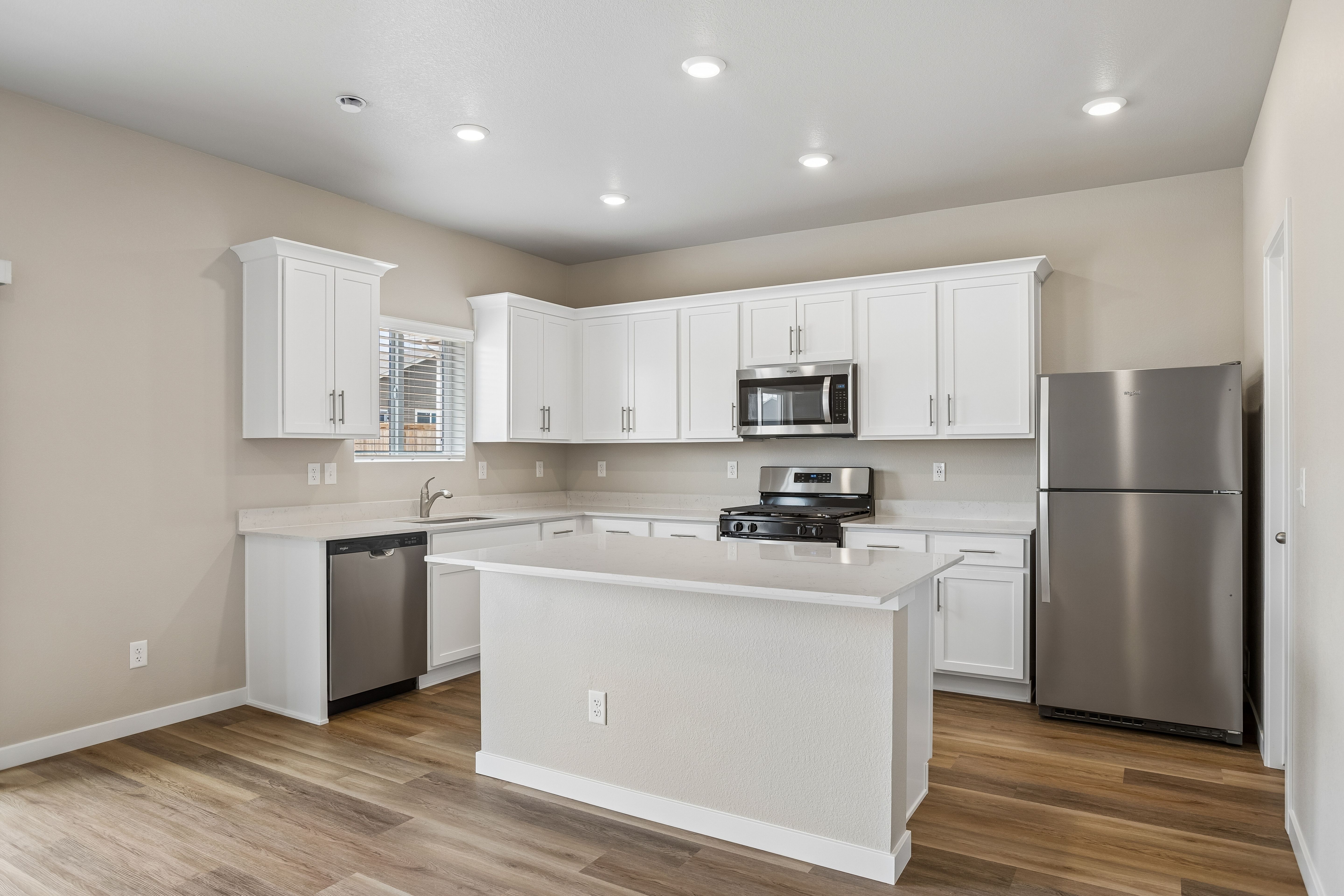 The kitchen has stainless steel appliances and plank flooring.