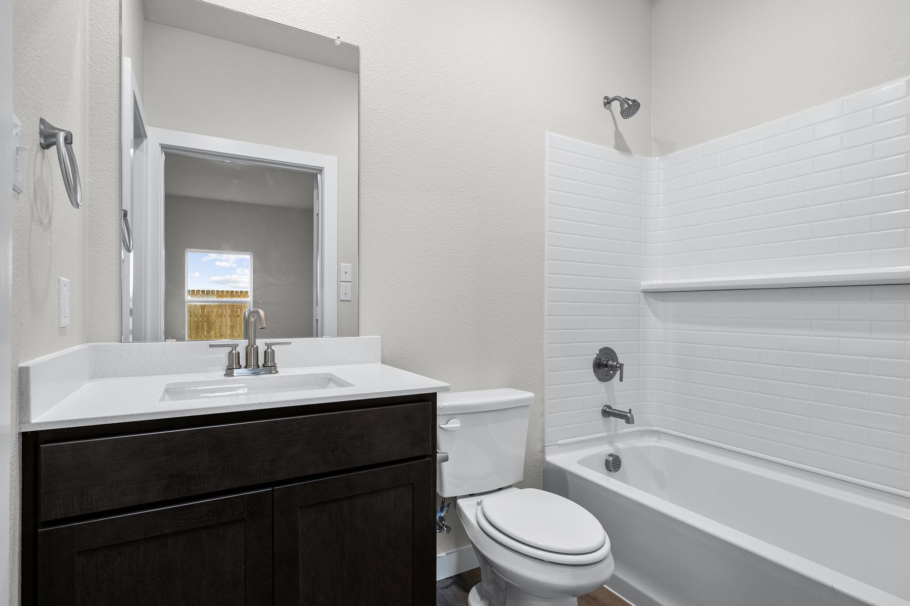 The master bathroom has a vanity and shower-tub combo.